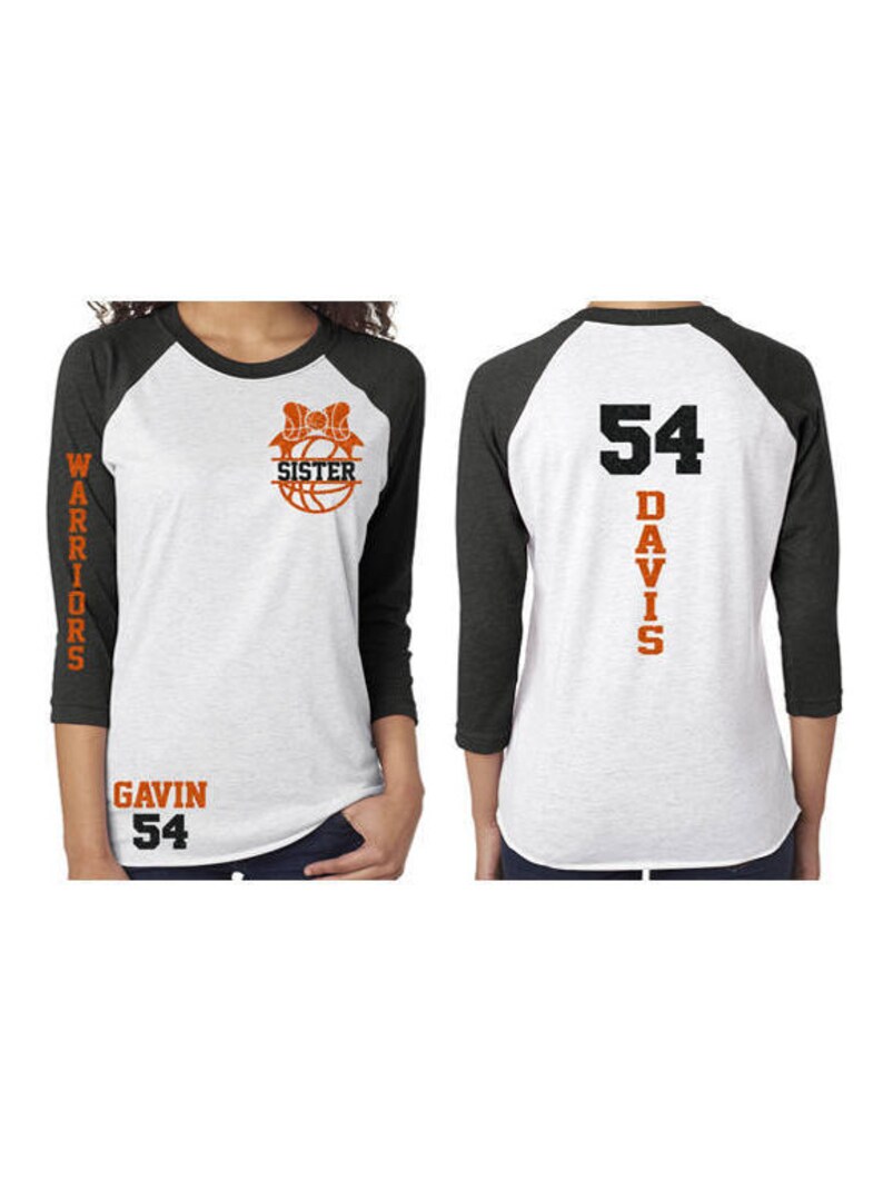 Pu&ograve; includere: Una maglietta da baseball bianca e nera con testo arancione. La parte anteriore della maglietta ha una palla da basket con un fiocco e il testo "Sorella". La parte posteriore della maglietta ha il numero "54" e il testo "Davis". La manica sinistra ha il testo "Warriors" e la parte inferiore della maglietta ha il testo "Gavin 54".