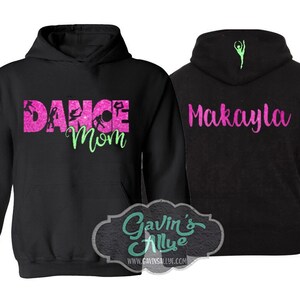 May include: Black hooded sweatshirt with pink glitter text that says "Dance Mom" and a green silhouette of a dancer. The back of the sweatshirt has pink glitter text that says "Makayla" and a green silhouette of a dancer.