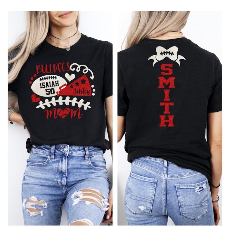 Op de afbeelding: Een zwart t-shirt met een voorzijde voorzien van een football, een megafoon en de tekst BULLDOGS, ISAIAH 50, ASHLEY en MOM in rood en wit. De achterzijde toont een football-icoon boven de verticale rode tekst SMITH.