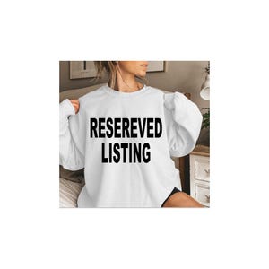 May include: A white long-sleeved crewneck sweatshirt featuring the black text "RESEREVED LISTING" printed in a bold, sans-serif font across the center of the chest. The garment has a standard fit with ribbed cuffs and a ribbed neckline.