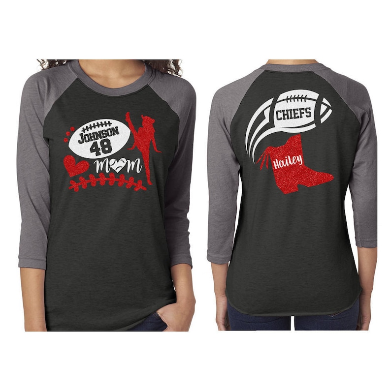 May include: Two black and grey baseball shirts with red glitter designs. The front shirt has a football, a cheerleader, a heart, and the text "Johnson 48 Mom". The back shirt has a football with the text "Chiefs" and a boot with the text "Hailey".