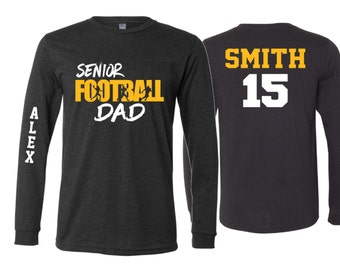 May include: Two long-sleeved shirts, one black with the text "Senior Football Dad" in yellow and the other black with the text "SMITH 15" in white.