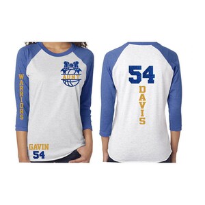 Pu&ograve; includere: Una maglietta da baseball bianca e blu con un design di pallacanestro e fiocco sul davanti. La parte posteriore della maglietta ha il numero 54 e il nome DAVIS stampato verticalmente sul retro. La maglietta ha un design a maniche raglan bianche e blu. Le parole "WARRIORS" sono stampate sulla manica sinistra e "GAVIN 54" sono stampate in basso a sinistra della maglietta.