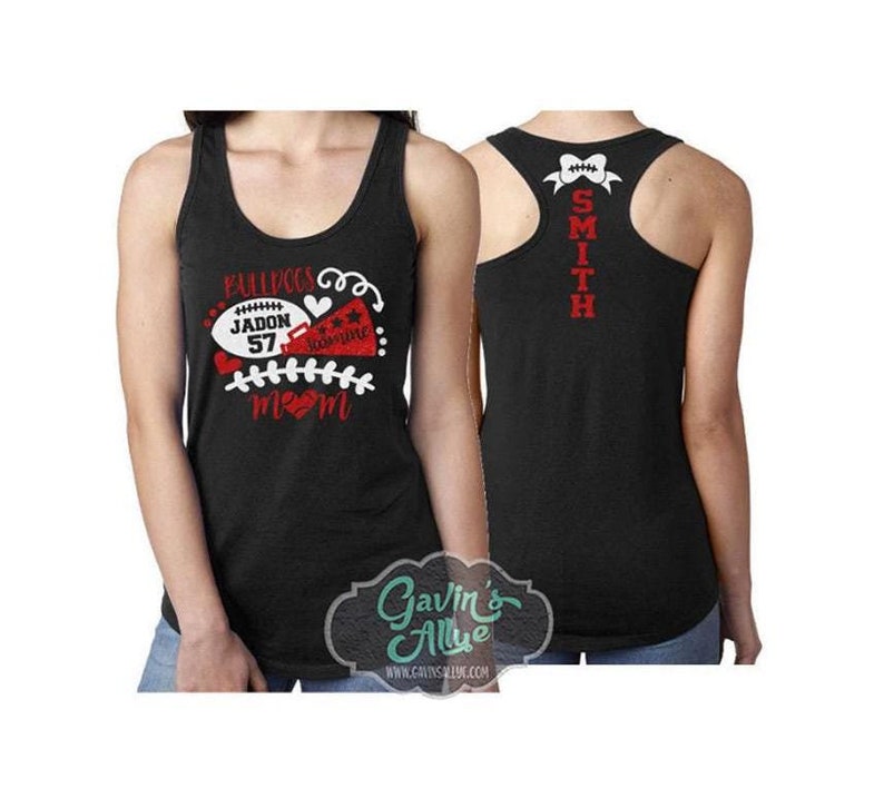 May include: Black tank top with red and white text that says "Bulldogs Jadon 57 Mom" and a football and a cheerleader's pom pom. The back of the tank top has the text "Smith" in red.