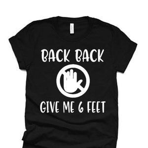 Puede incluir: Camiseta negra con texto blanco que dice "Back Back" con un círculo y una mano tachada, y "Give Me 6 Feet".