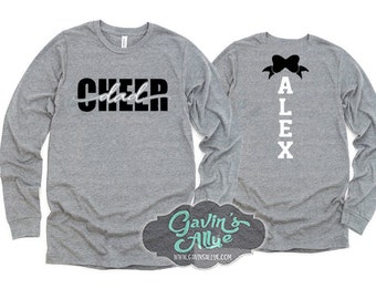 Könnte beinhalten: Zwei Langarmshirts, eines grau mit schwarzem Text, der "cheer dad" sagt, und das andere grau mit einer schwarzen Schleife und weißem Text, der "ALEX" sagt.
