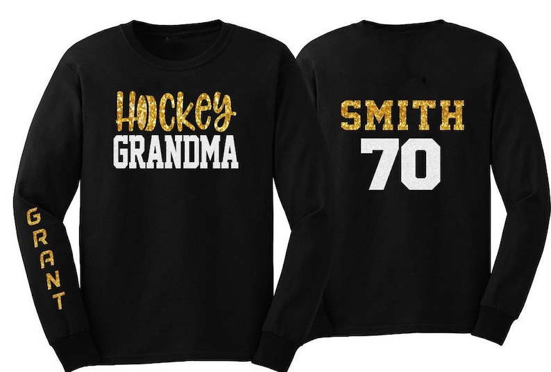 May include: Two black long-sleeved shirts with gold glitter lettering. One shirt says "Hockey Grandma" and the other says "Smith 70".