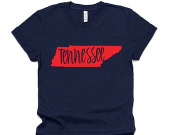 Puede incluir: Una camiseta azul marino con un contorno rojo del estado de Tennessee y la palabra "Tennessee" en letras negras.