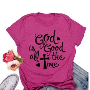 May include: A pink t-shirt with a black graphic that says "God is good all the time" with a cross and hearts.