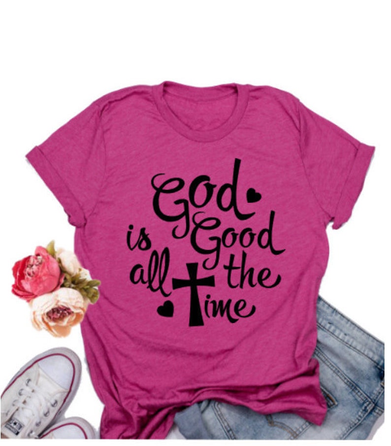 May include: A pink t-shirt with a black graphic that says "God is good all the time" with a cross and hearts.