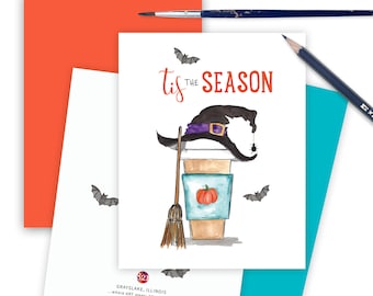 May include: A watercolor illustration of a coffee cup with a witch's hat on top. The cup has a pumpkin sticker on it and a broom is next to it. The text "Tis the Season" is written above the cup.