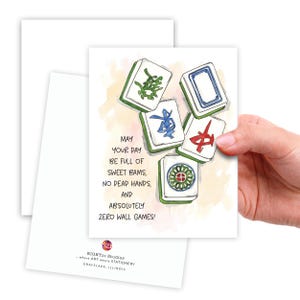 Peut inclure: Carte de v&oelig;ux avec une illustration &agrave; l'aquarelle de tuiles de Mahjong. La carte pr&eacute;sente des symboles verts, bleus et rouges. Le texte se lit comme suit : "Que votre journ&eacute;e soit pleine de doux bams, pas de mains mortes, et absolument z&eacute;ro jeux de mur !"