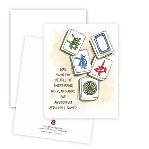 Peut inclure: Carte de v&oelig;ux avec des illustrations &agrave; l'aquarelle de tuiles de Mahjong. La carte contient le texte : "May your day be full of sweet bams, no dead hands, and absolutely zero wall games !" Le logo Eight21 Studios est en bas.