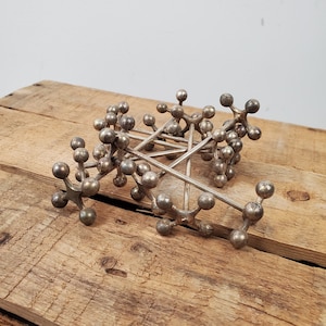 May include: A set of silver metal star-shaped objects with multiple points. The objects are arranged in a pile on a wooden surface.