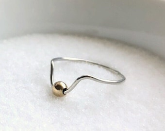 May include: A silver ring with a wavy band and a gold bead accent.