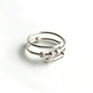 May include: Silver ring with three textured beads on a twisted band.