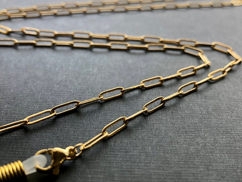May include: A gold chain with a spring clasp. The chain is made of small, oval-shaped links.