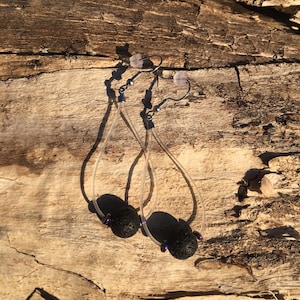 May include: A pair of black lava rock earrings with clear and silver wire, and purple iridescent beads.