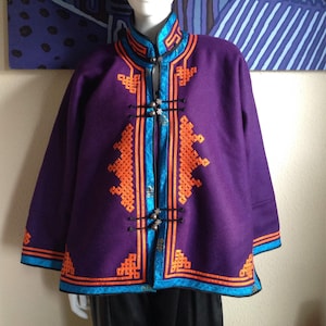 May include: A purple jacket with orange and blue embroidery. The jacket has a mandarin collar and a front closure with decorative buttons.