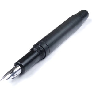 May include: A black fountain pen with a silver nib. The pen has a sleek, cylindrical design and is set against a white background. The nib is visible, showcasing its fine point.