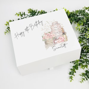 Może przedstawiać: Białe pudełko prezentowe z różową i złotą ilustracją tortu, kwiatów i szampana. Na pudełku widnieje napis "Happy 18th Birthday Scarlett".