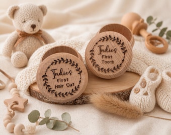 Puede incluir: Cajas de recuerdo de madera con texto grabado y diseño de hojas. Una caja dice "Indie's First Hair Cut" y la otra "Indie's First Tooth". Un osito de peluche de ganchillo, un sonajero y patucos para bebé también están en la imagen.
