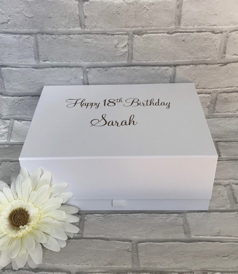 May include: White gift box with a white ribbon and the text "Happy 18th Birthday Sarah" printed on the top.