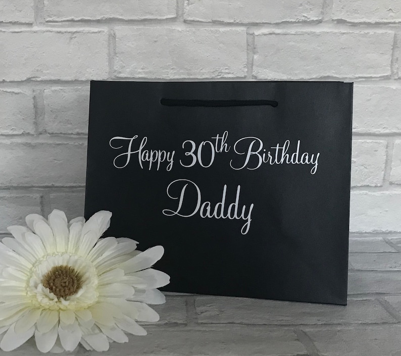May include: Black gift bag with white text that reads "Happy 30th Birthday Daddy".