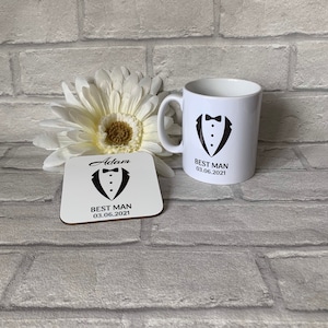 May include: White ceramic mug with a black tuxedo graphic and the text "Best Man 03.06.2021". A matching white coaster with the text "Adam Best Man 03.06.2021" and a tuxedo graphic.