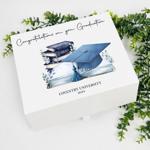 May include: White gift box featuring an illustration of a blue graduation cap and books. The text on the box reads "Congratulations on your Graduation" and "Coventry University 2024".