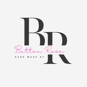 May include: Logo for Button Rose, featuring the letters "BR" in a bold, black serif font. The words "Button Rose" are in a cursive, pink font, with "HAND MADE BY" in a smaller, black font below.