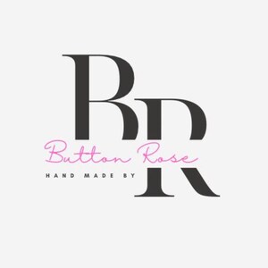 May include: Logo for Button Rose, featuring the letters "BR" in a bold, black serif font. The words "Button Rose" are in a cursive, pink font, with "HAND MADE BY" in a smaller, black font below.
