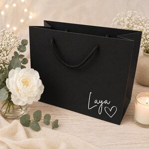 Peut inclure: Un sac cadeau noir avec le nom "Laya" &eacute;crit en blanc avec un c&oelig;ur. Il poss&egrave;de des poign&eacute;es en corde noire. Le fond comprend des fleurs, une bougie et un &eacute;clairage doux.