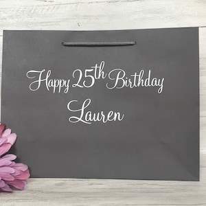 May include: Gray gift bag with white text that says "Happy 25th Birthday Lauren".