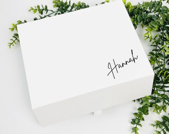 May include: White gift box with a black handwritten name "Hannah" on the top.