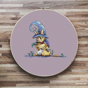 May include: A cross-stitch pattern of a rabbit wearing a purple and blue wizard hat and holding a carrot. The rabbit is standing on a purple background with green grass and a carrot on the ground.