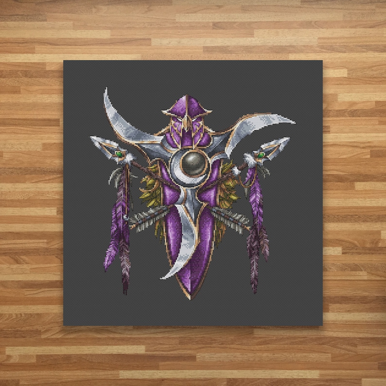 May include: A purple and silver embroidered design with a central circle and two feathers on either side. The design is on a dark gray background.