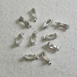 Peut inclure: Dix anneaux en métal de couleur argent, chacun avec une forme ovale unique. Les anneaux sont disposés sur une surface blanche.