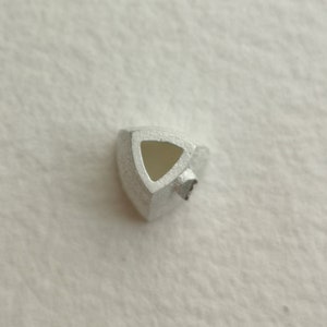 May include: A silver triangular pendant with a hollow center. The pendant has a smooth, metallic finish.