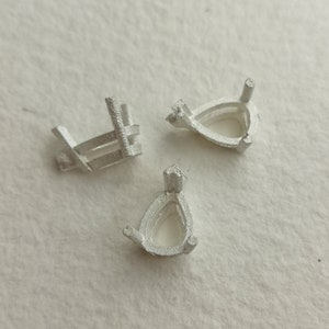 Può includere: Tre montature in metallo color argento per l'incastonatura di pietre preziose a forma di pera. Le montature sono progettate per tenere la pietra preziosa saldamente in posizione.