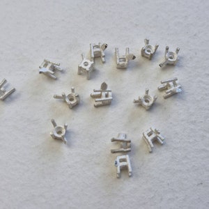 May include: A collection of 15 silver-toned prong settings for jewelry making. The settings are designed to hold a gemstone or other embellishment.