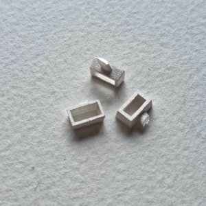 May include: Three silver-toned metal clasps, each with a rectangular shape and a small opening. The clasps are designed for attaching jewellery or other items.