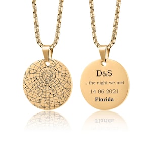 May include: Gold-colored pendant necklace with a round charm. One side features a star map design, while the other side is engraved with "D&S ...the night we met 14 06 2021 Florida". The necklace has a delicate chain.