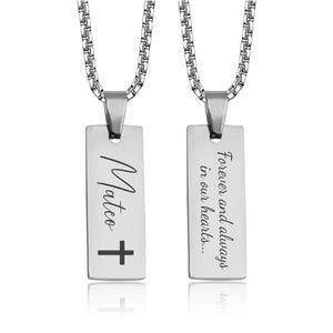 May include: A silver-colored rectangular pendant necklace with a chain. One side of the pendant has the name "Mateo" and a cross. The other side reads "Forever and always in our hearts..."
