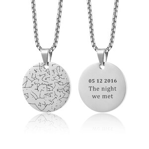 Könnte beinhalten: Eine silberfarbene Halskette mit einem runden Anhänger. Eine Seite des Anhängers zeigt ein Sternbildmuster, die andere Seite den Text "05 12 2016 The night we met". Die Kette hat ein Kettenglied-Design. Der Anhänger hat einen Durchmesser von ca. 2,5 cm.