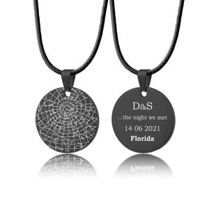 Könnte beinhalten: Zwei schwarze runde Anhänger-Halsketten. Ein Anhänger zeigt ein Sternkarten-Design, der andere hat den Text "D&S ...the night we met 14 06 2021 Florida". Beide Anhänger sind an schwarzen Kordeln befestigt.