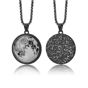 May include: A black necklace with a round pendant. One side of the pendant features a detailed image of the moon, while the other side displays a constellation map. The necklace has a black chain.