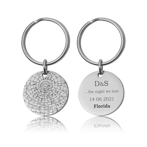May include: Two silver keychains with round pendants. One pendant features a star map design, the other has the initials "D&S", the text "...the night we met", date "14 06 2021", and the word "Florida".