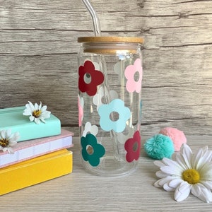 May include: A clear glass reusable water bottle with a bamboo lid and a straw. The bottle is decorated with colourful flower decals in shades of pink, red, green, and blue.