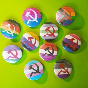 Op de afbeelding: Negen ronde pinnen met verschillende gekleurde achtergronden en een zwart-wit afbeelding van een hamer en sikkel op elk. De pinnen zijn in een cirkel op een groene achtergrond gerangschikt.